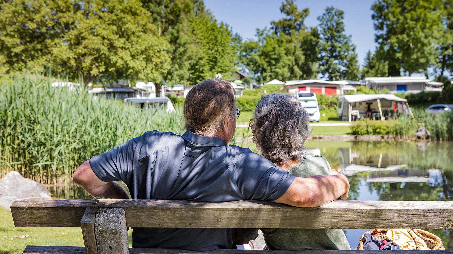 Älteres Paar sitzt auf einer Bank am Teich im Camp Mondseeland